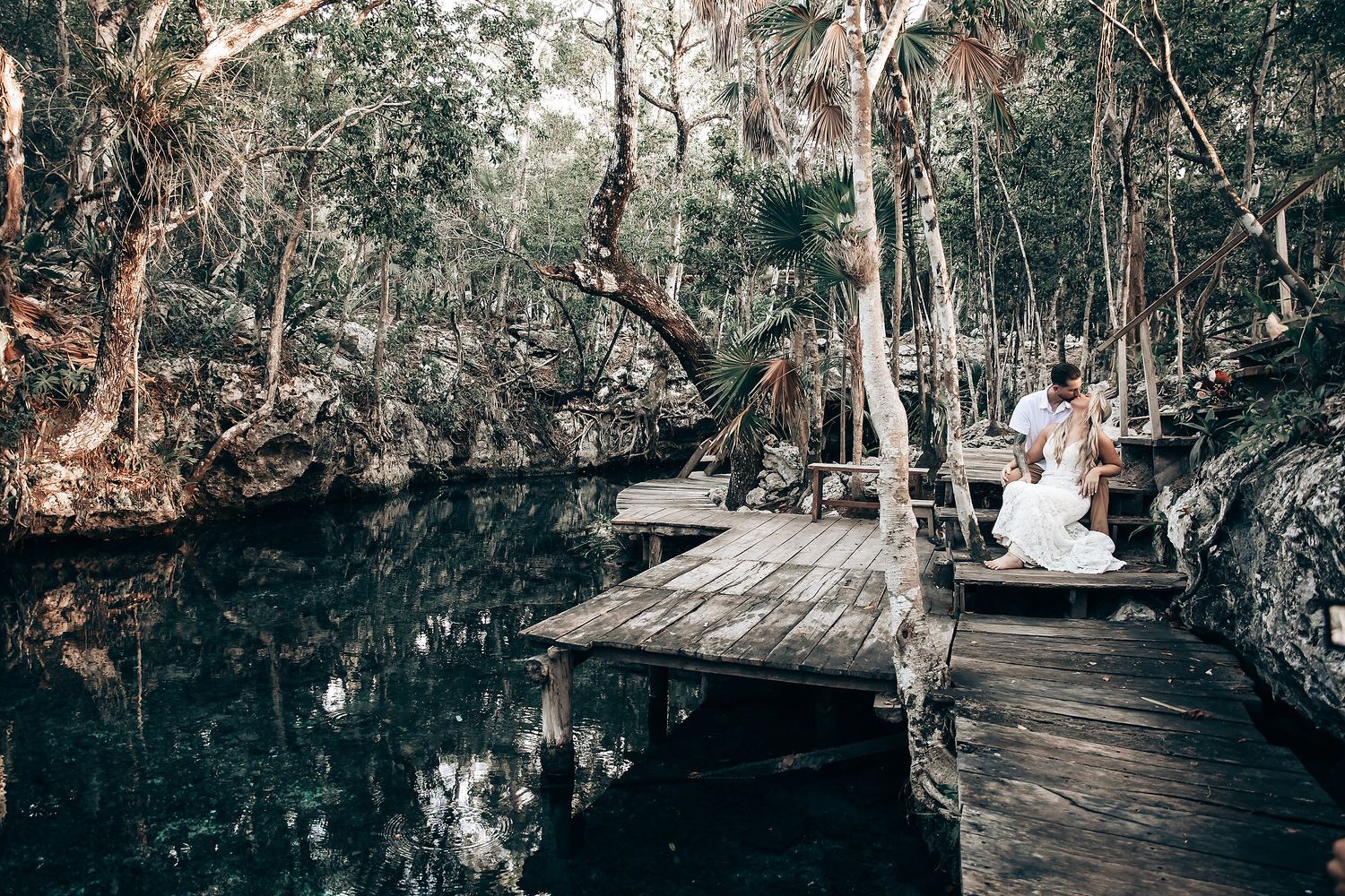 A scenic wooden boardwalk winds through a lush forest with tall trees and natural greenery.