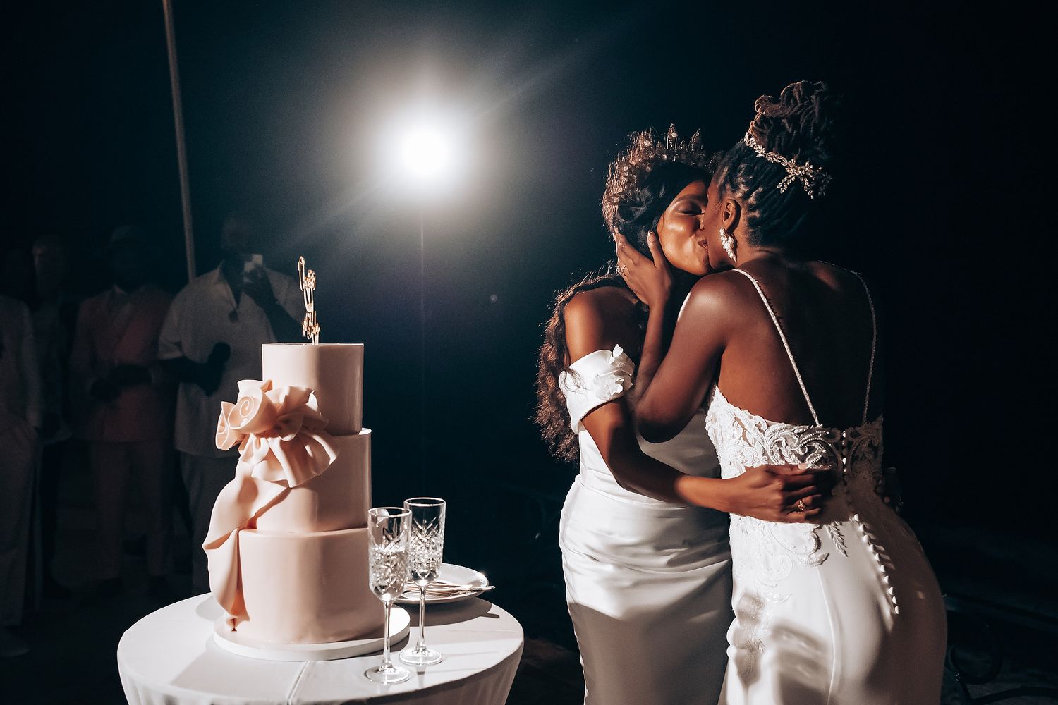 Wedding cake cutting ceremony captured in dramatic nighttime lighting.