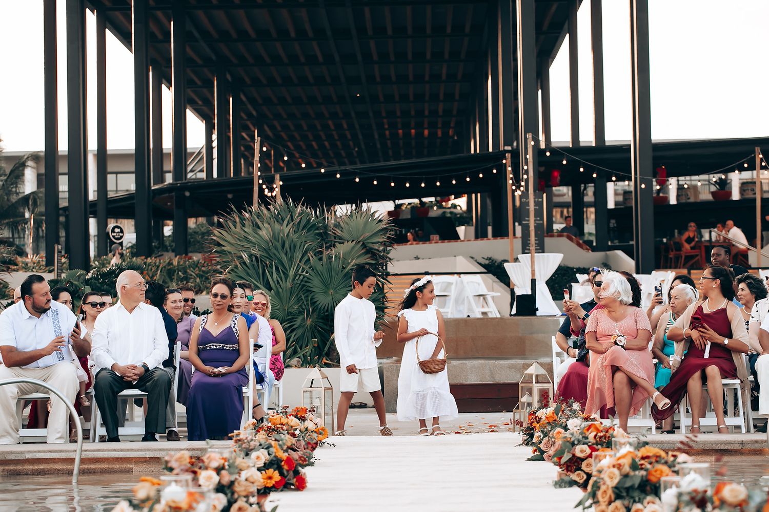 Wedding reception setup with long tables decorated with floral arrangements under string lights.
