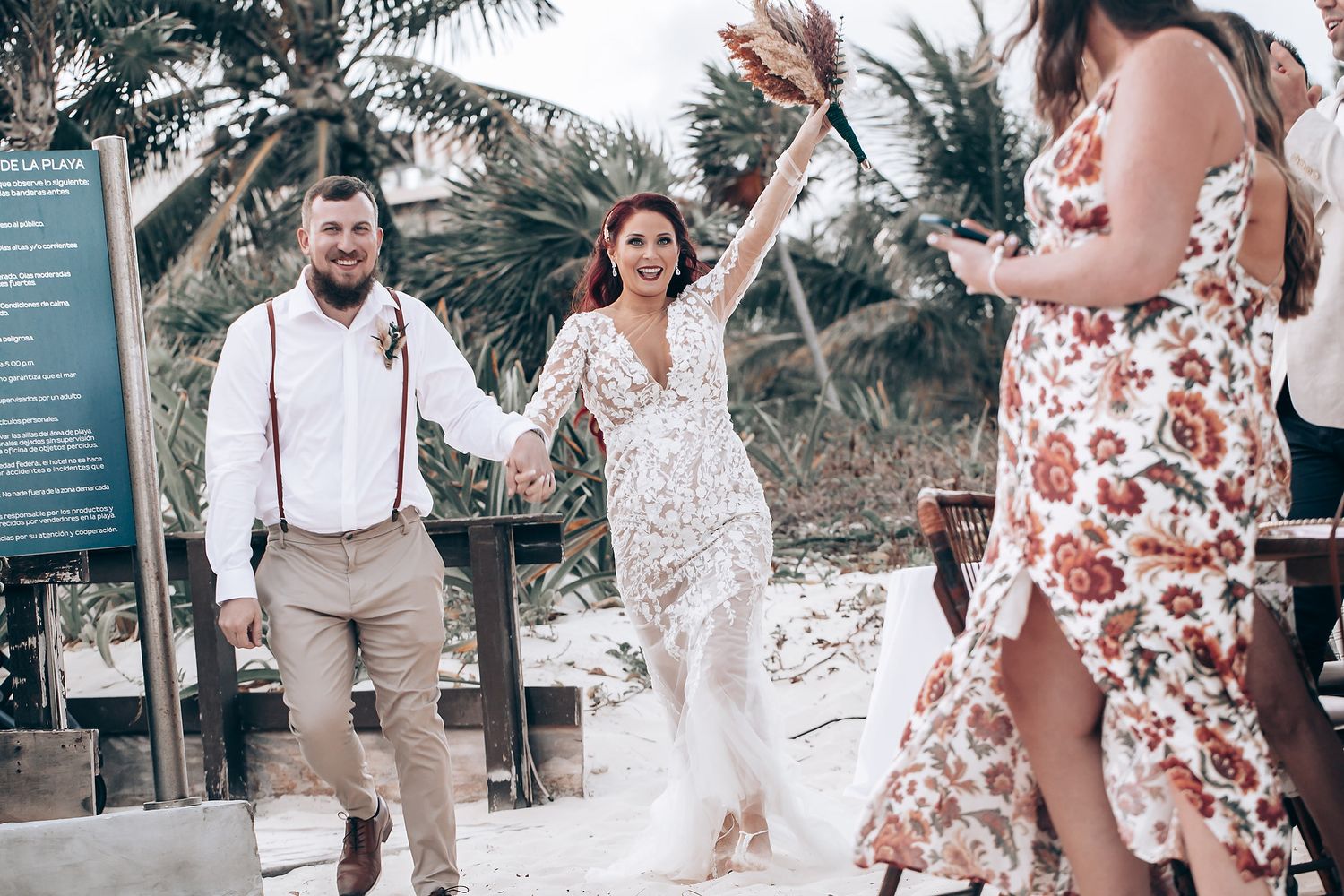 Wedding party celebrates with joyful dancing at tropical beach reception.
