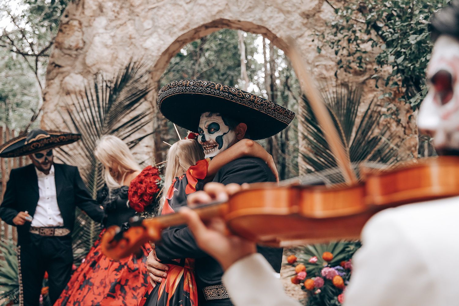 Musicians perform at an outdoor wedding ceremony under stone arches with gothic styling.