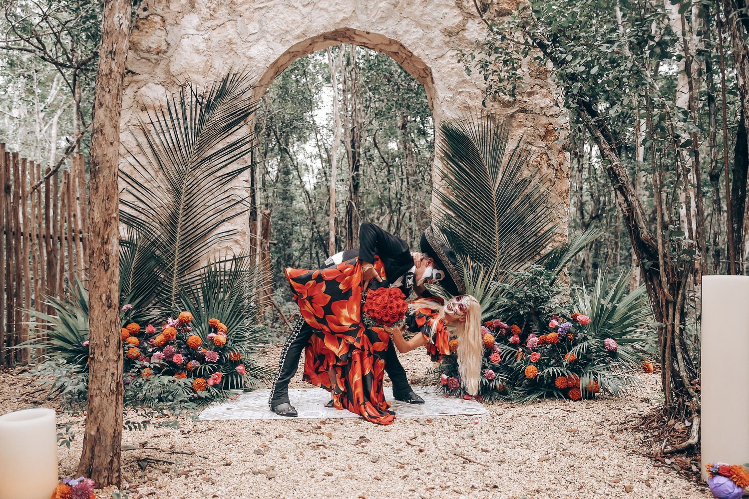 Wide angle shot of a Day of the Dead themed photo session in a forest setting with stone walls.