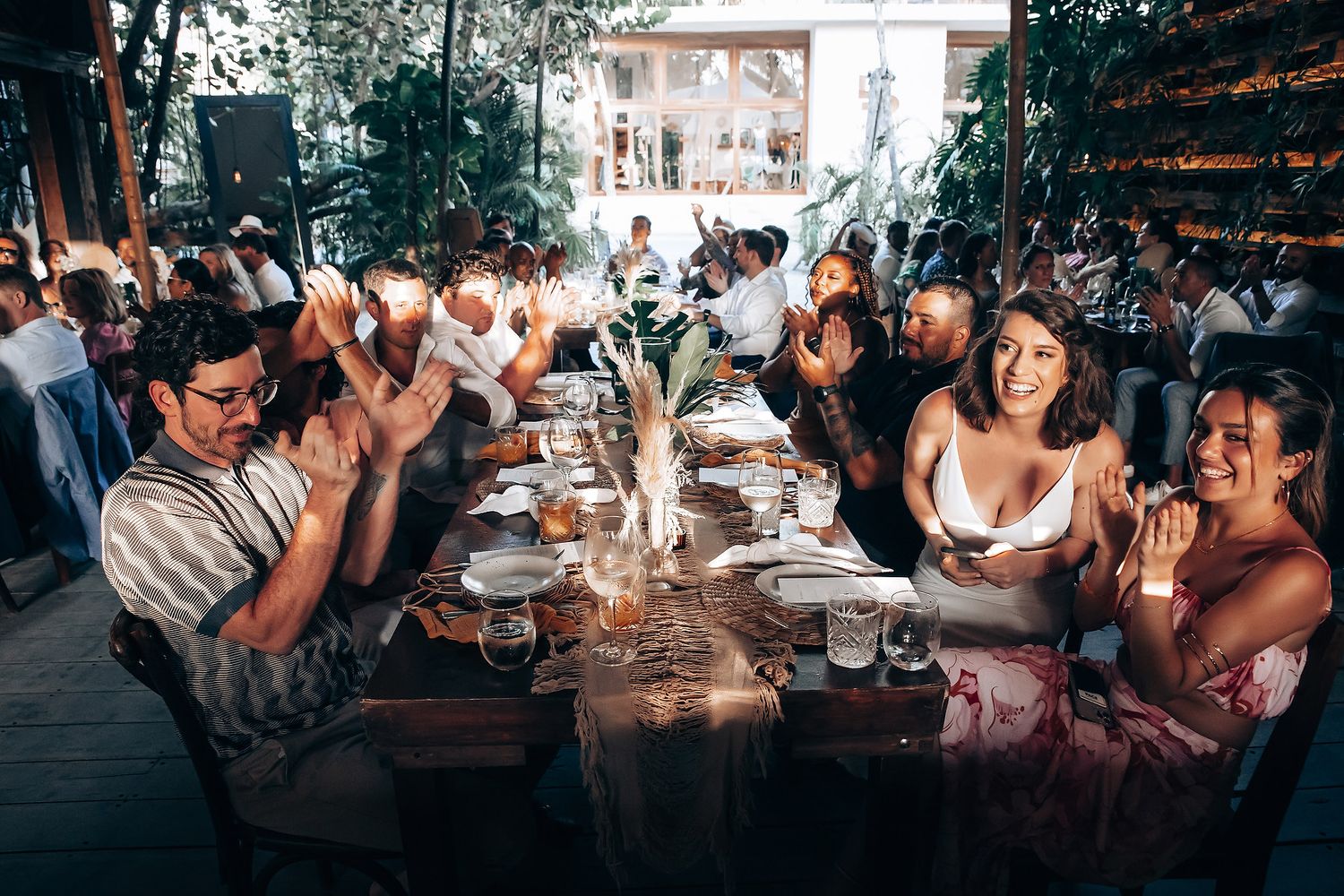 Guests enjoying a festive outdoor wedding reception under natural lighting.