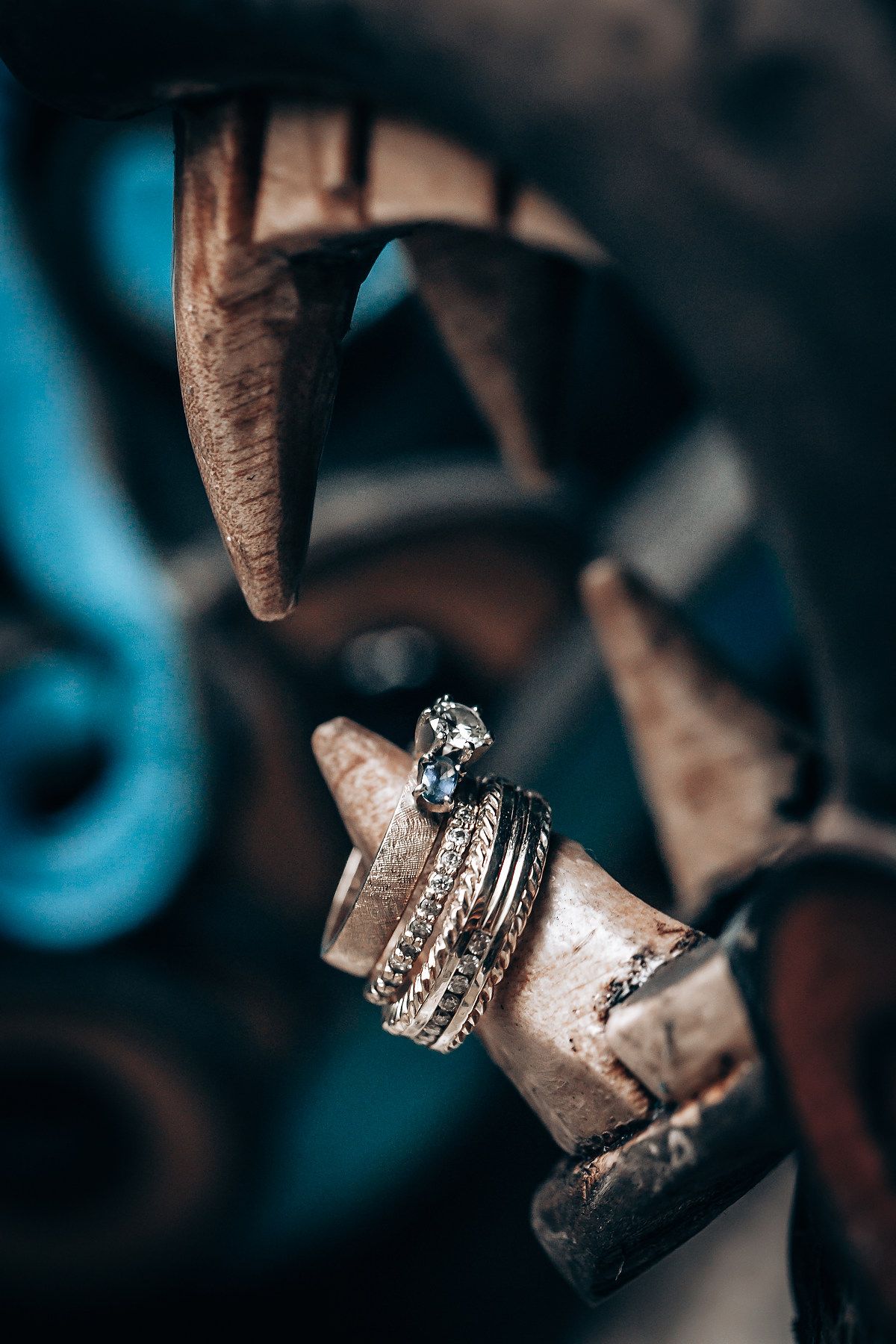 Silver diamond engagement rings and wedding bands displayed on a rustic carved wooden ceremonial artifact.