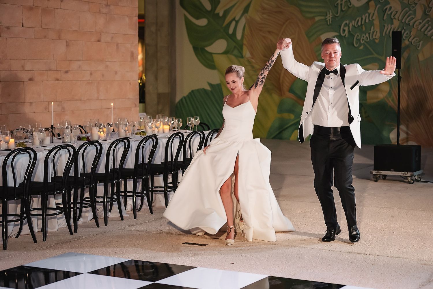 Wedding reception setup in an industrial venue with exposed brick walls and modern black chairs.