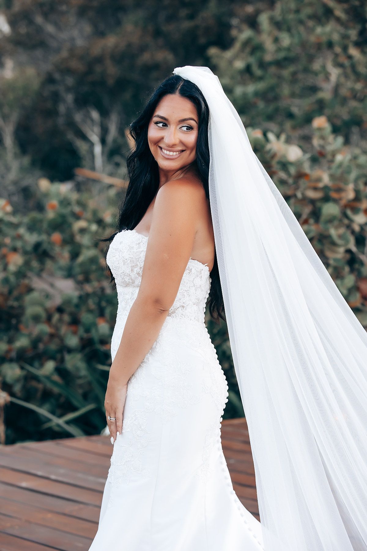 Close-up portrait of bride in white lace wedding dress with flowing veil.