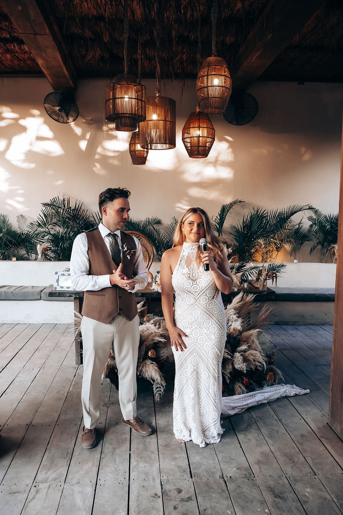 A romantic couple dances together in a rustic barn venue with wooden floors and hanging lanterns.