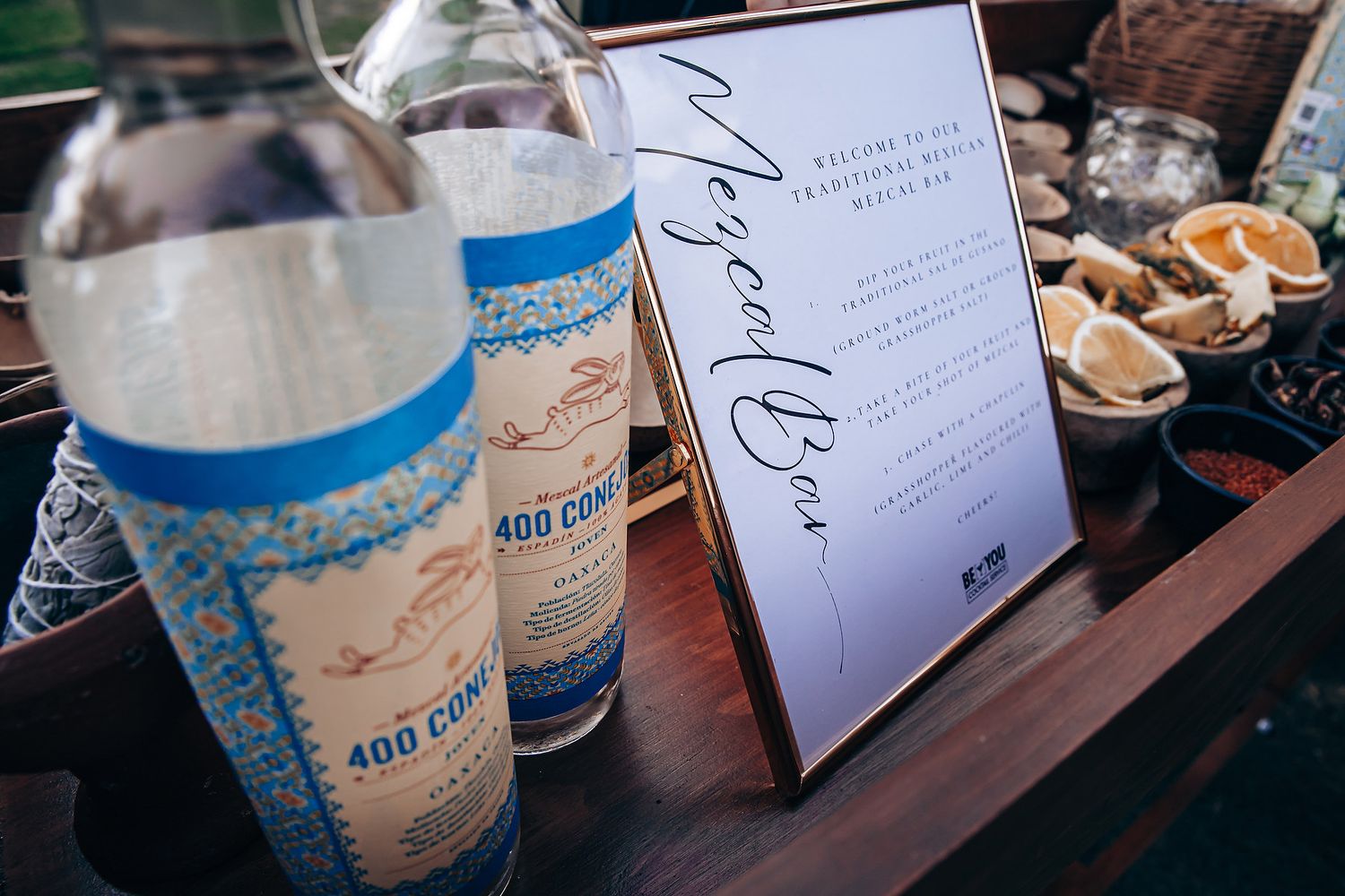 Elegant table setting with wedding invitations and blue glass candle holders arranged on a dark wooden surface.