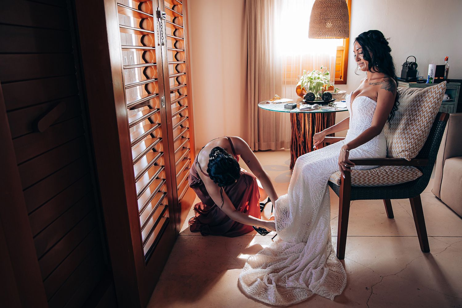 Sunlit room with wooden shutters where a white wedding dress flows gracefully.