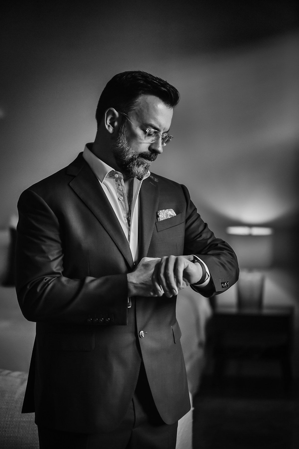 Dramatic black and white portraits of a groom adjusting his formal attire.