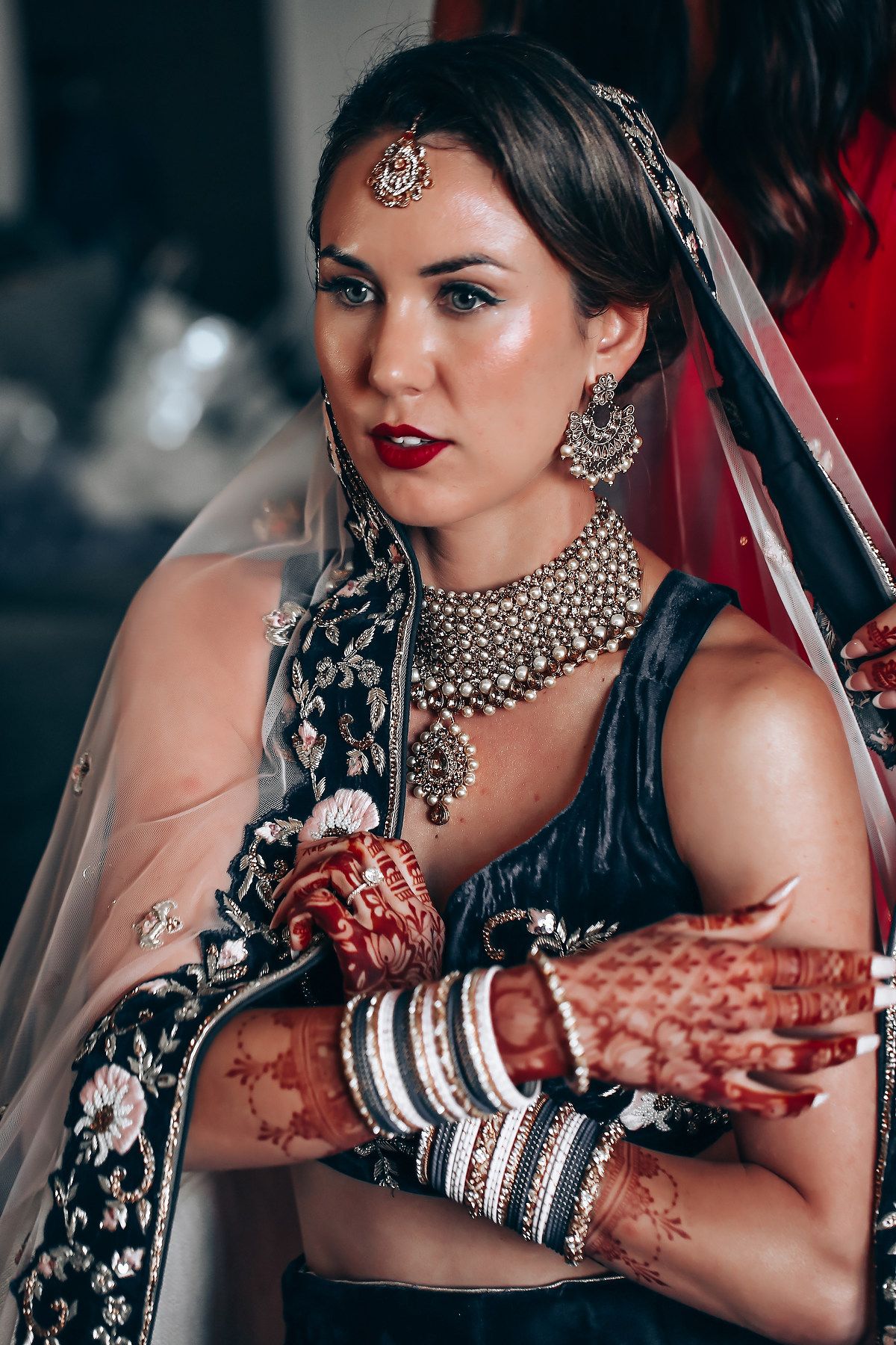 Bride wearing traditional Indian jewelry and black embroidered lehenga.