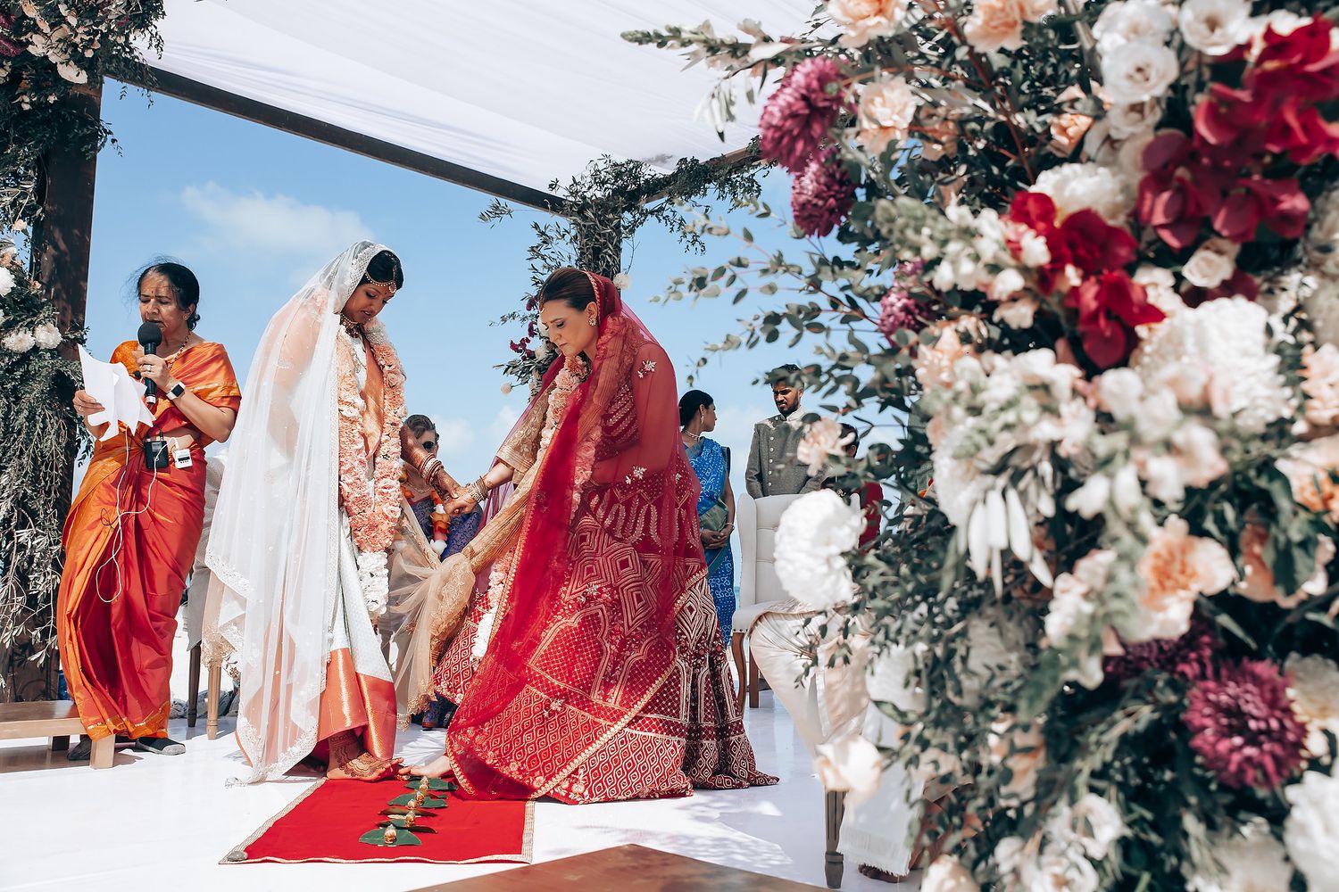 Panoramic view of beach wedding setup with floral arrangements and white fabric canopy.