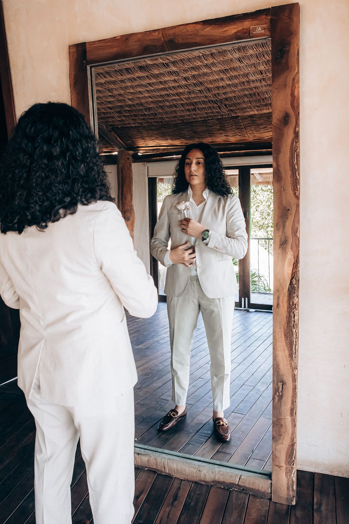 Person in white outfit reflected in mirrors along rustic wooden hallway.