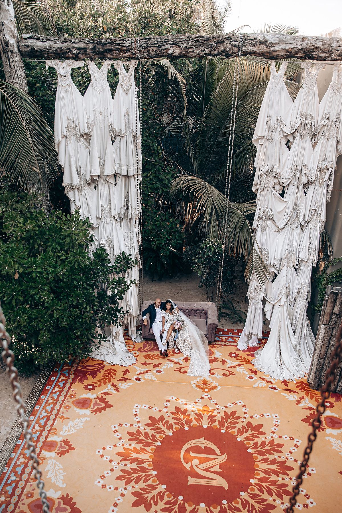 A series of white ghost-like figures hang from above around a circular orange pattern on a beige carpet.