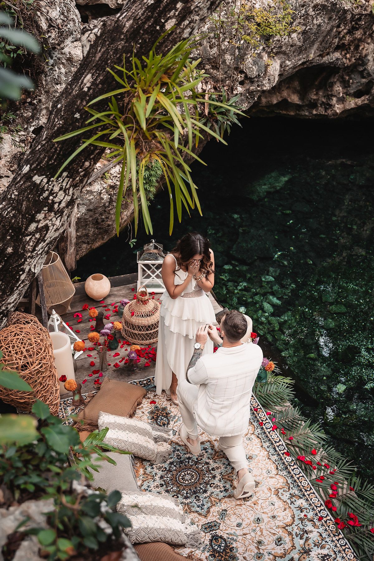 Beautifully decorated proposal setting with lanterns and flowers against natural cave backdrop.
