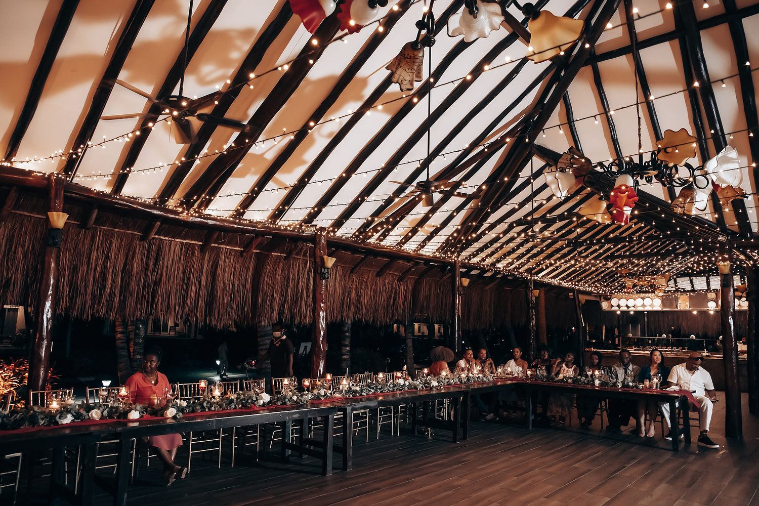 Wide angle view of rustic wedding reception venue with wooden beams and rows of tables.
