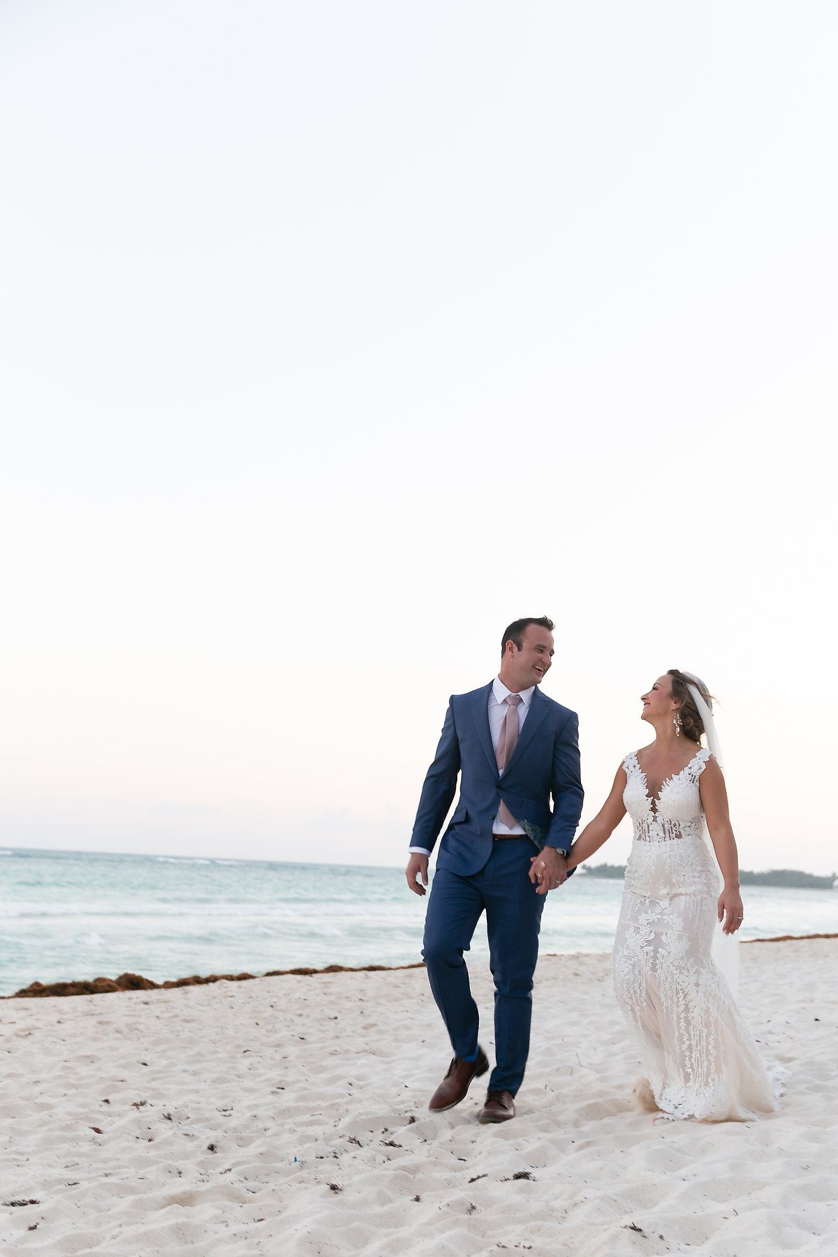 Couple walking and playing together on a pristine white sandy beach during sunset.