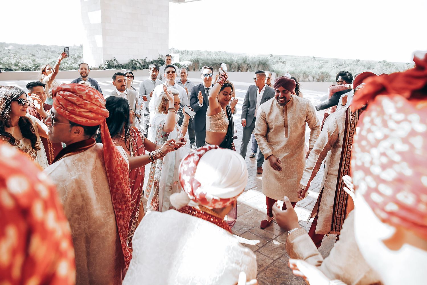A panoramic view of a traditional Indian wedding ceremony with guests in colorful attire gathered outdoors.