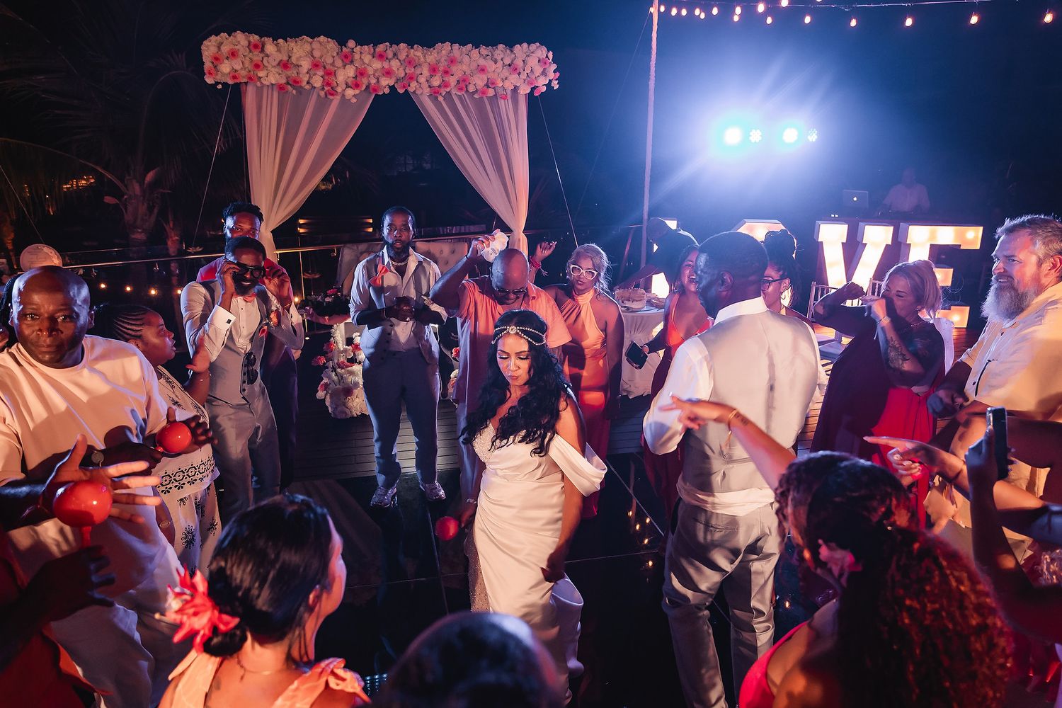 Wedding reception dance party with pink floral decor and string lights creating a festive atmosphere.