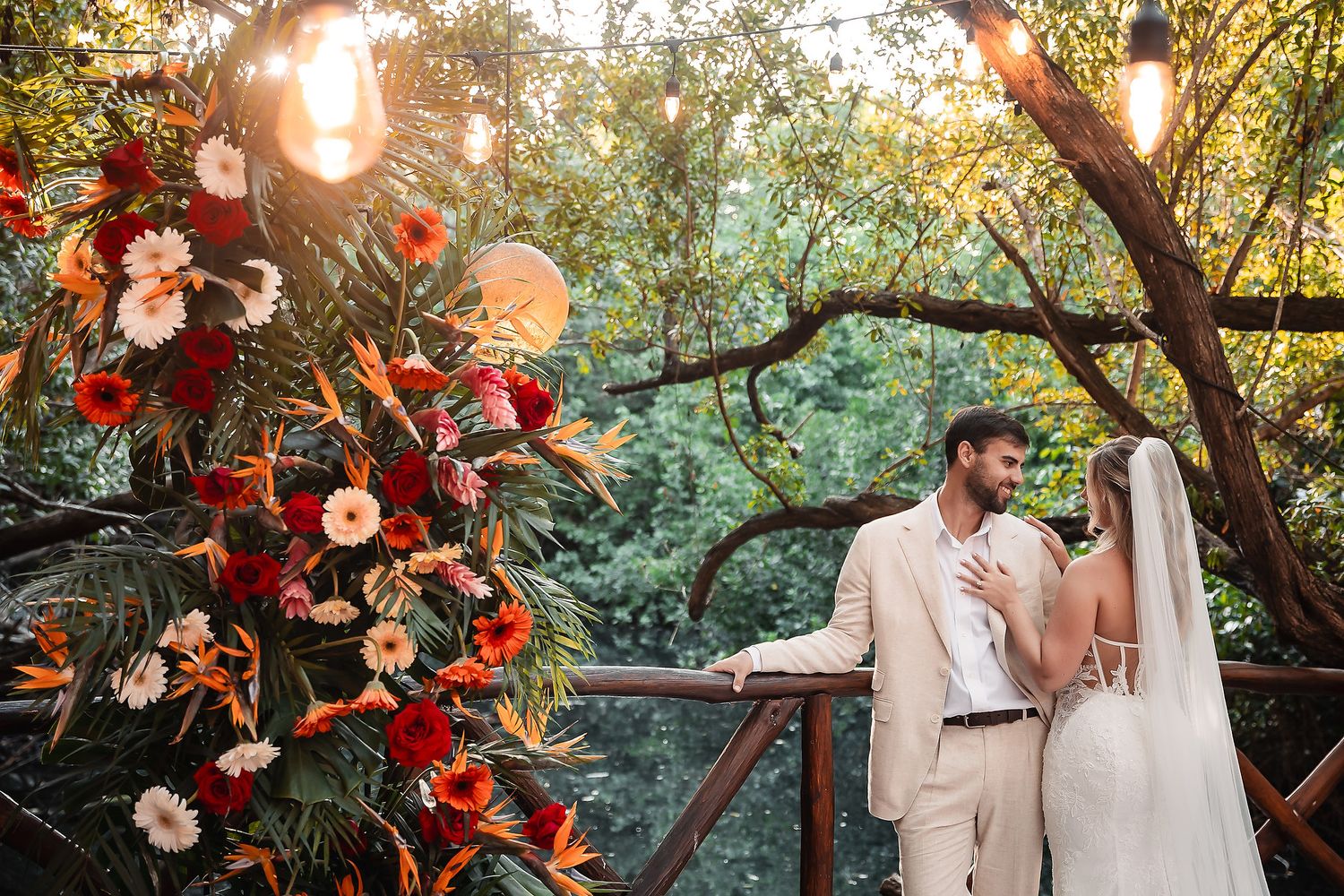Garden wedding scene with red floral arrangements and glowing lights creating magical ambiance.