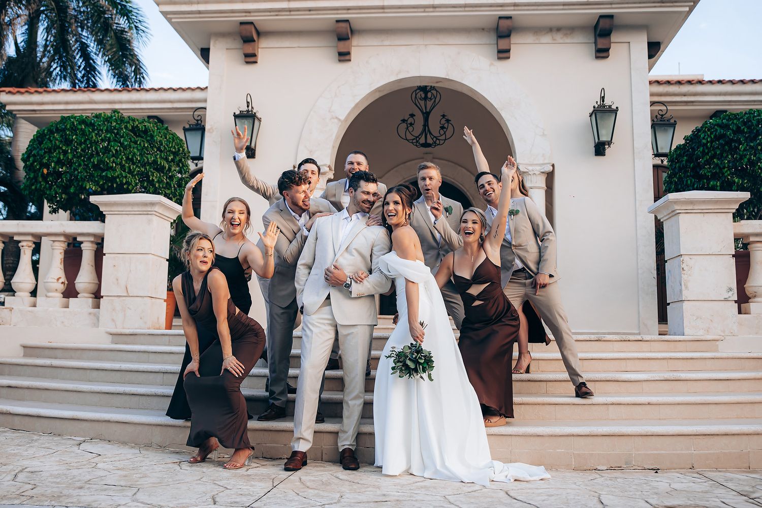 Wedding celebration outside Mediterranean-style venue with stone archways.