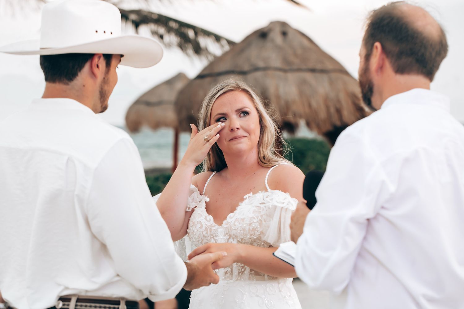 Wedding celebration outdoors with guests in white and khaki attire under string lights.