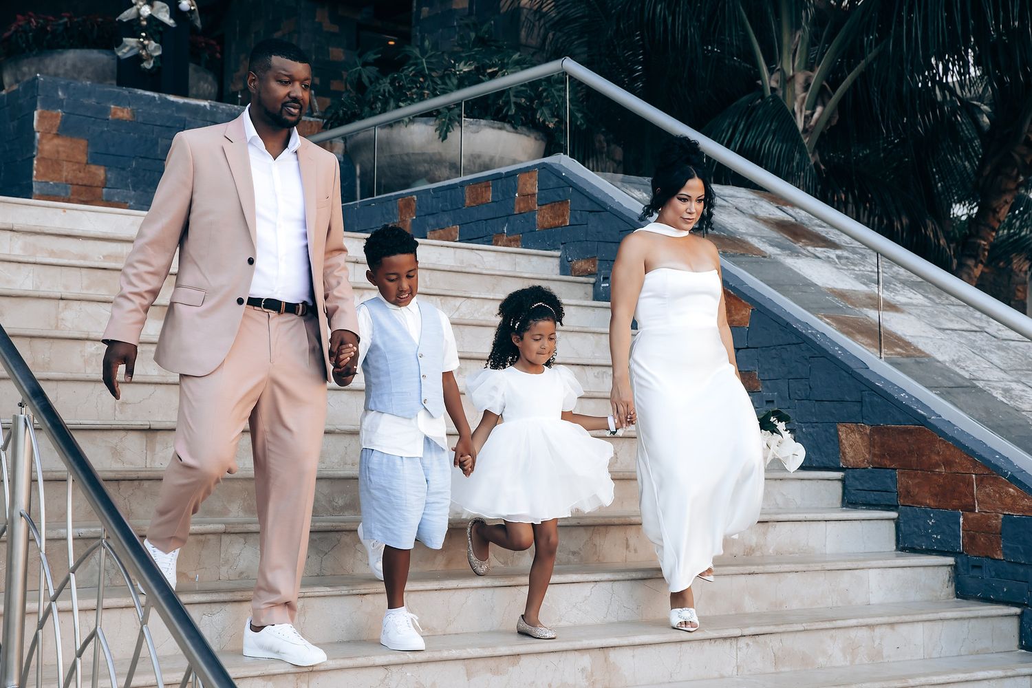 Couple in matching white and beige outfits descend outdoor stone steps during a photo session.