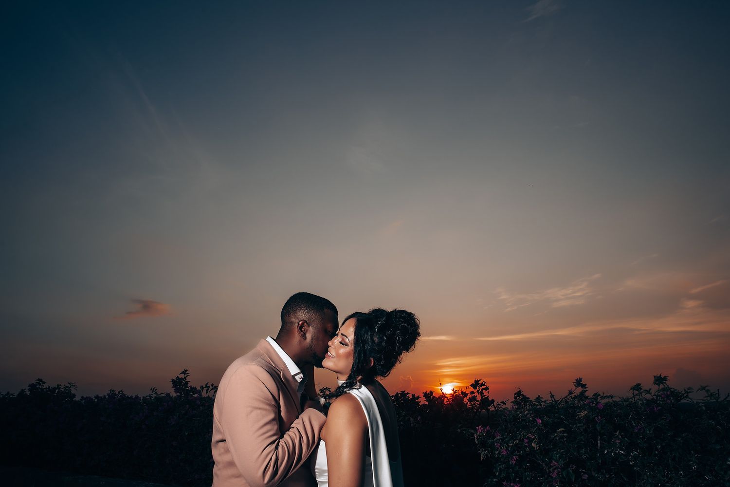Silhouettes against a dramatic sunset sky during wedding photography session.