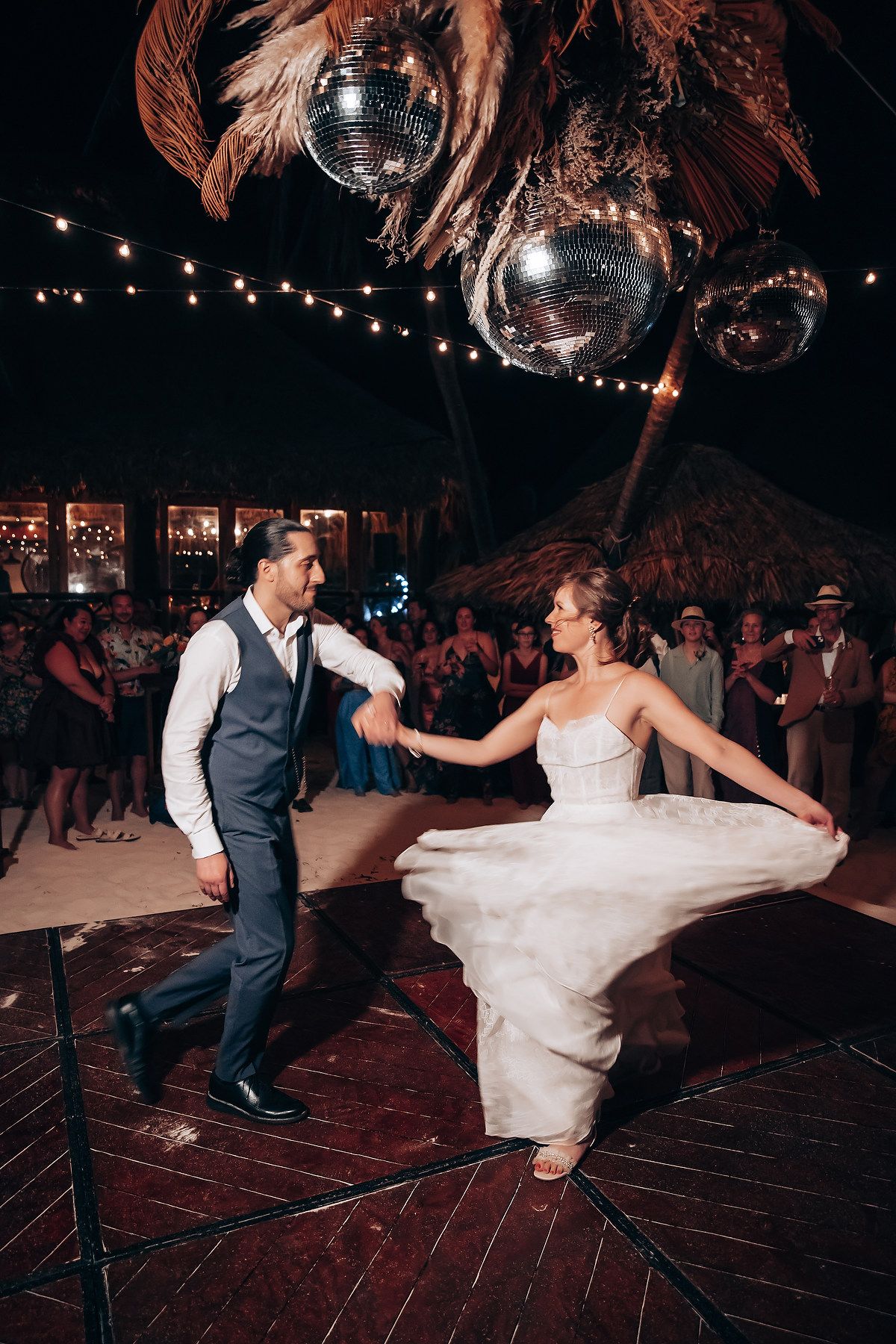 Wedding couple dancing under disco balls and string lights at an outdoor evening reception.