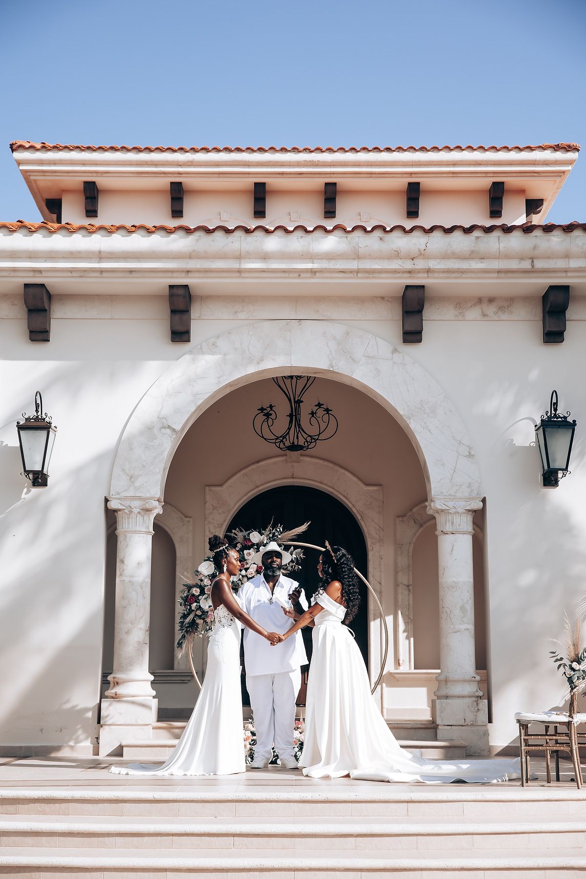 Elegant wedding ceremony under Mediterranean-style white arches with terra cotta roof tiles.