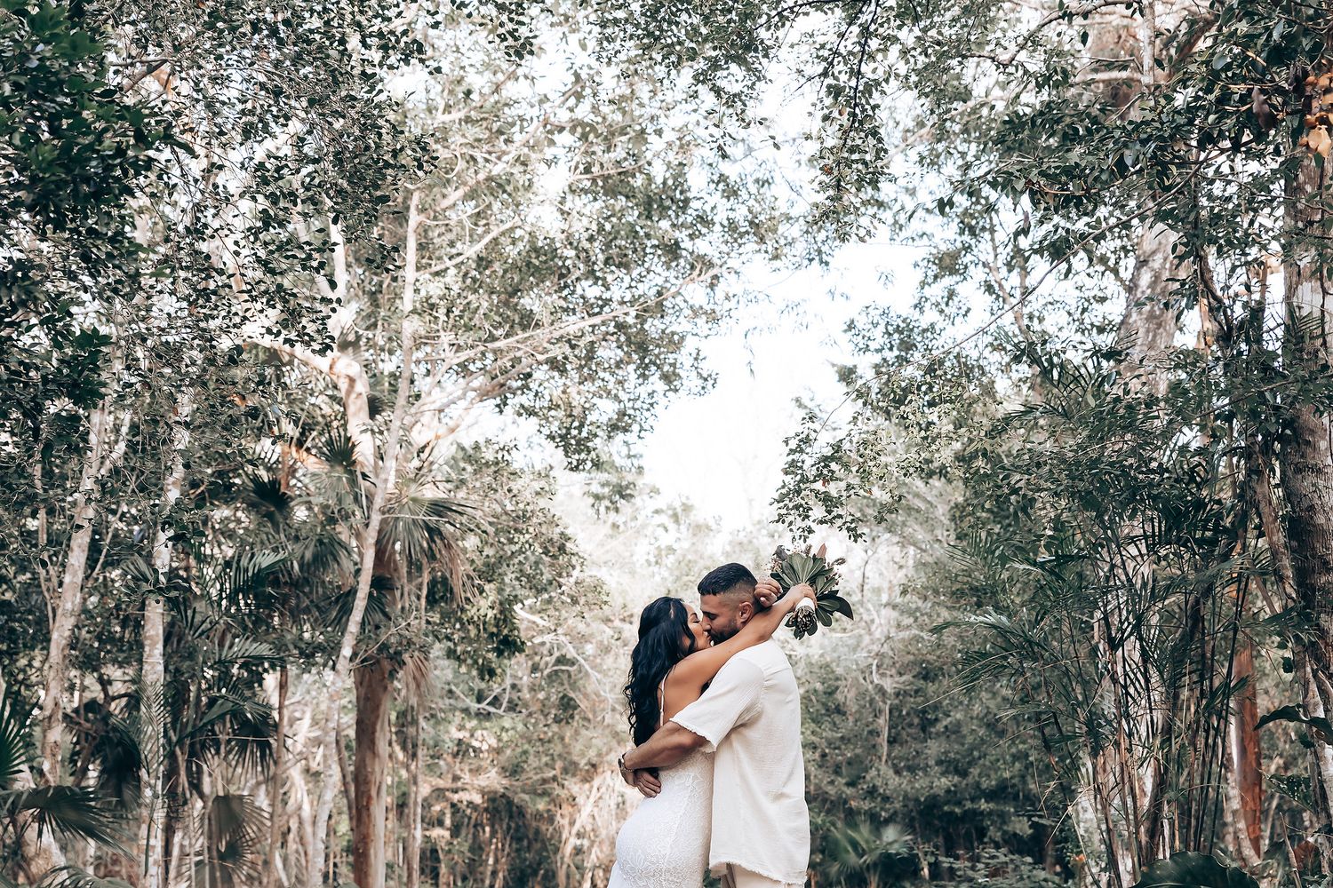 Romantic outdoor photo session by a tranquil water's edge surrounded by trees.