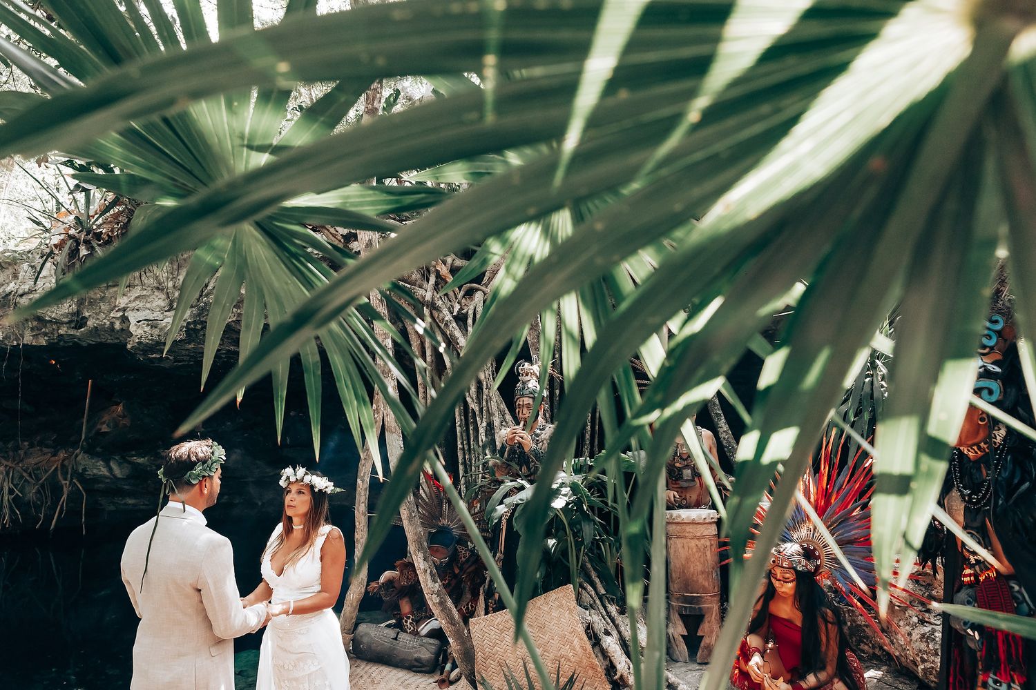 Outdoor wedding ceremony space decorated with palm leaves and natural elements in a garden setting.