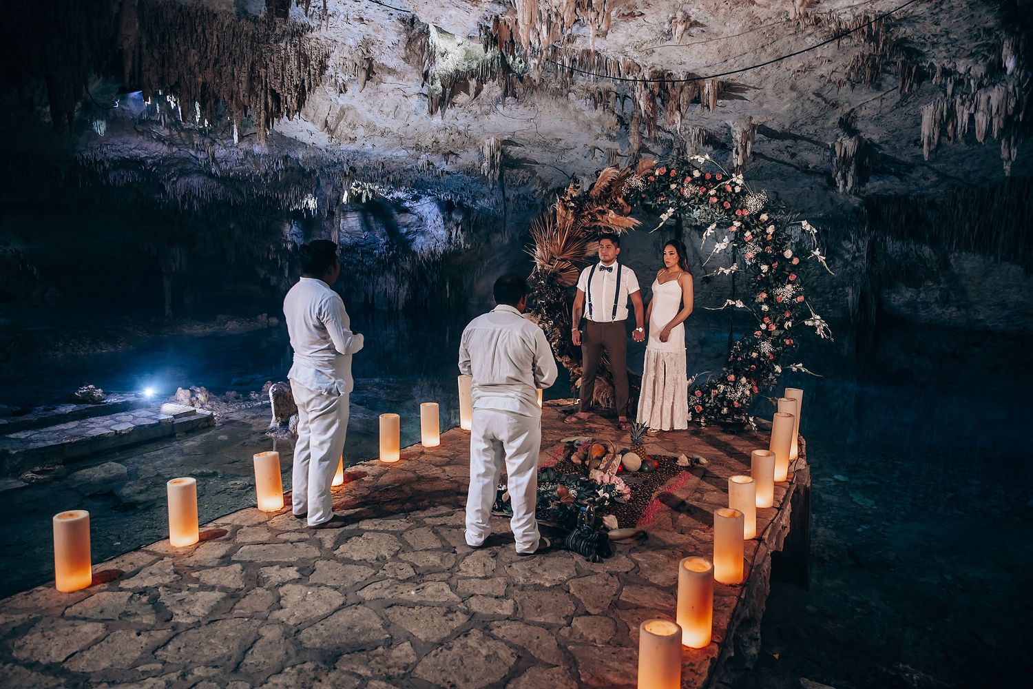 A romantic candlelit walkway leads through a dimly lit cave with luminarias creating a warm, intimate atmosphere.