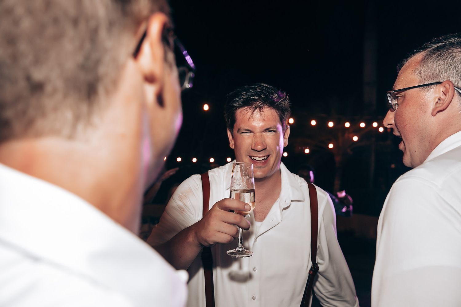 Wedding celebration under twinkling lights during nighttime festivities.