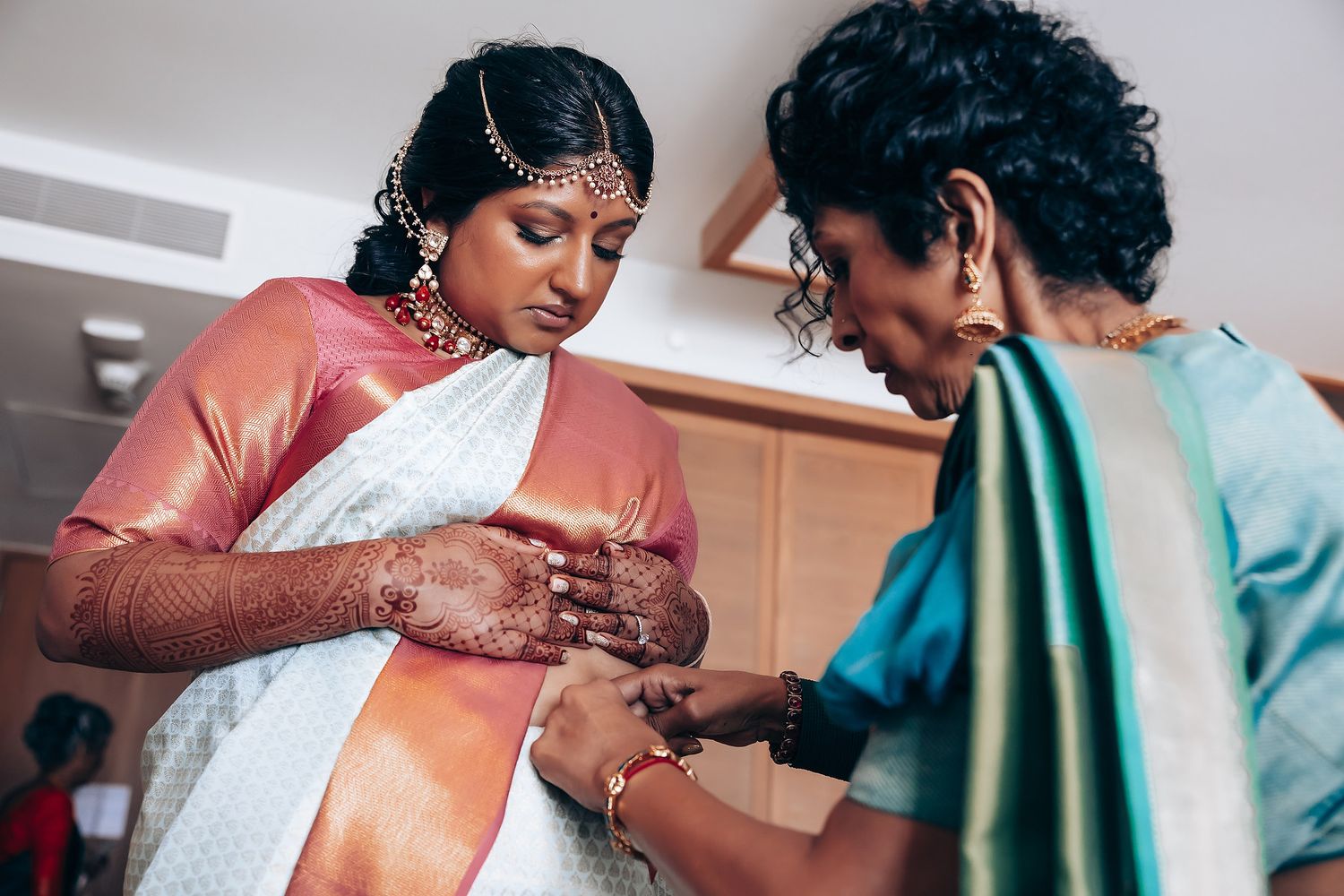 Traditional Indian wedding preparation with detailed henna application on hands.