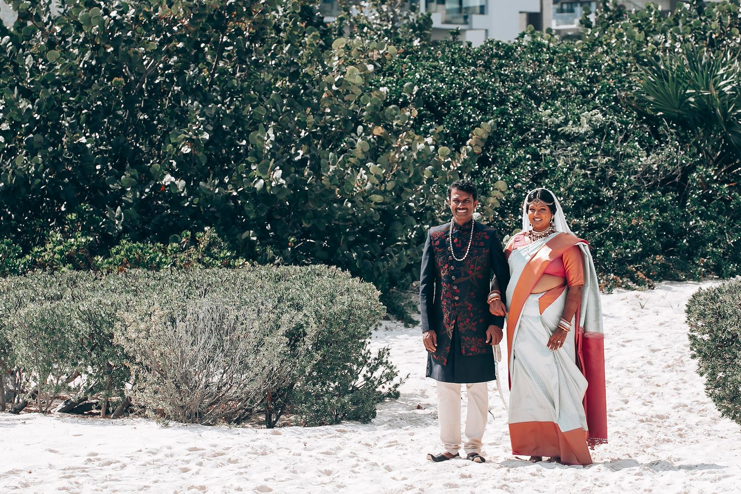 Couple in traditional Indian formal wear walking along garden path.