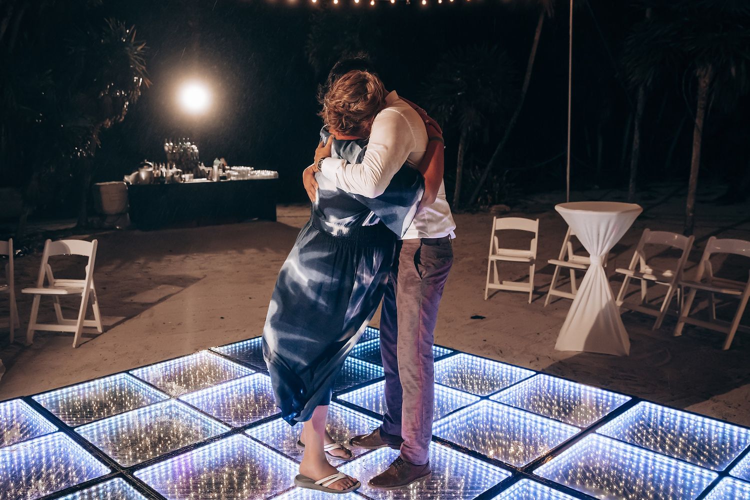 Wedding guests dancing on a glowing LED dance floor during an evening reception.