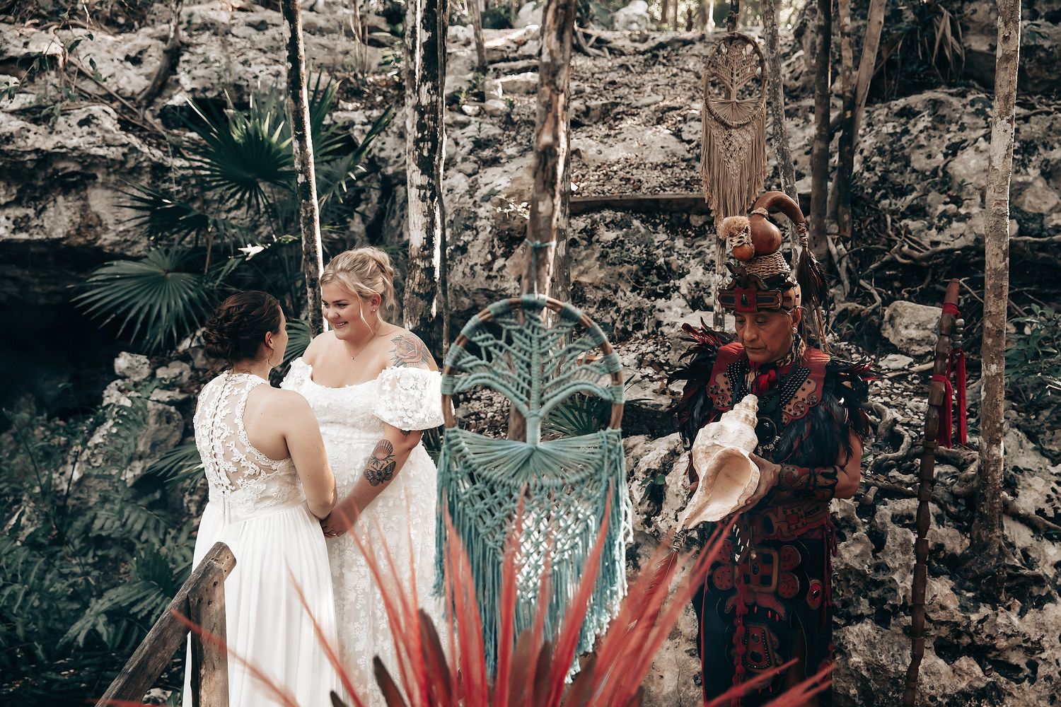 The image depicts a bride and groom posing in a tropical, lush garden setting, surrounded by vibrant foliage and decorative elements.