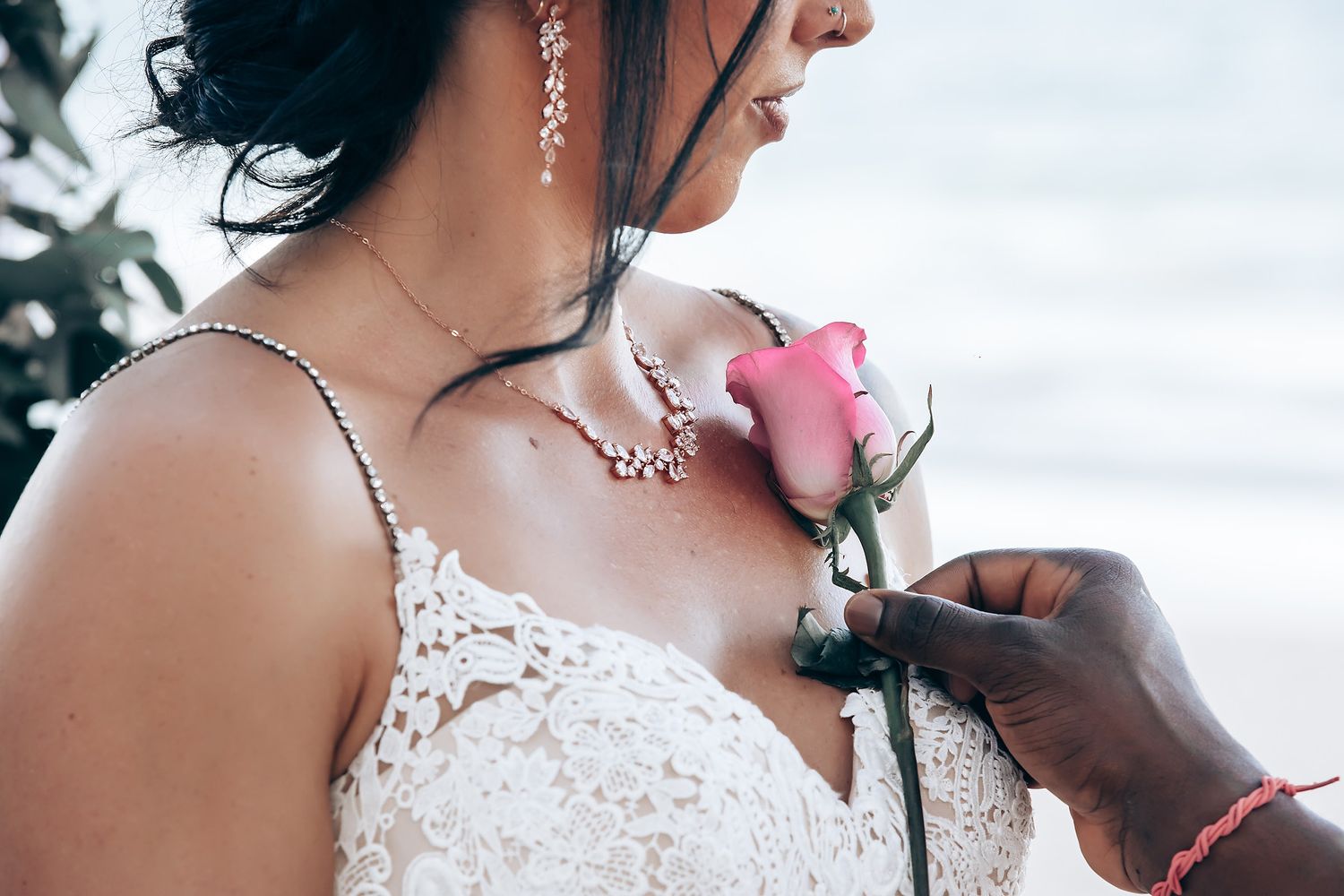 A close-up image of a bride's face as she is having her makeup applied, with a pink flower visible.