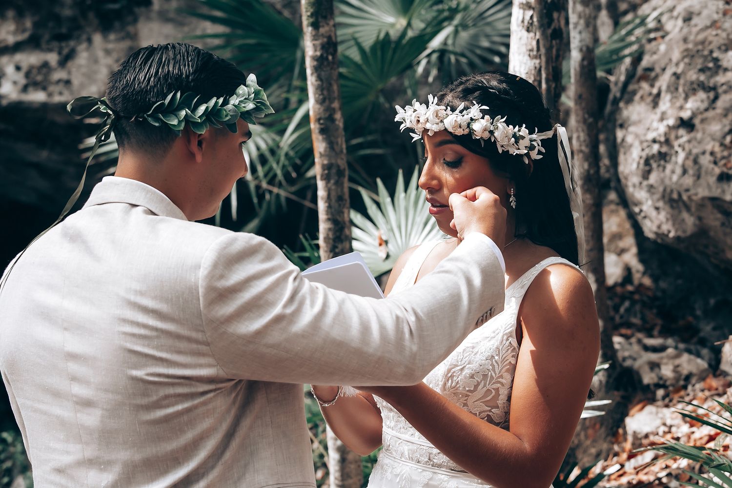 A couple shares a tender moment during their outdoor forest wedding ceremony.