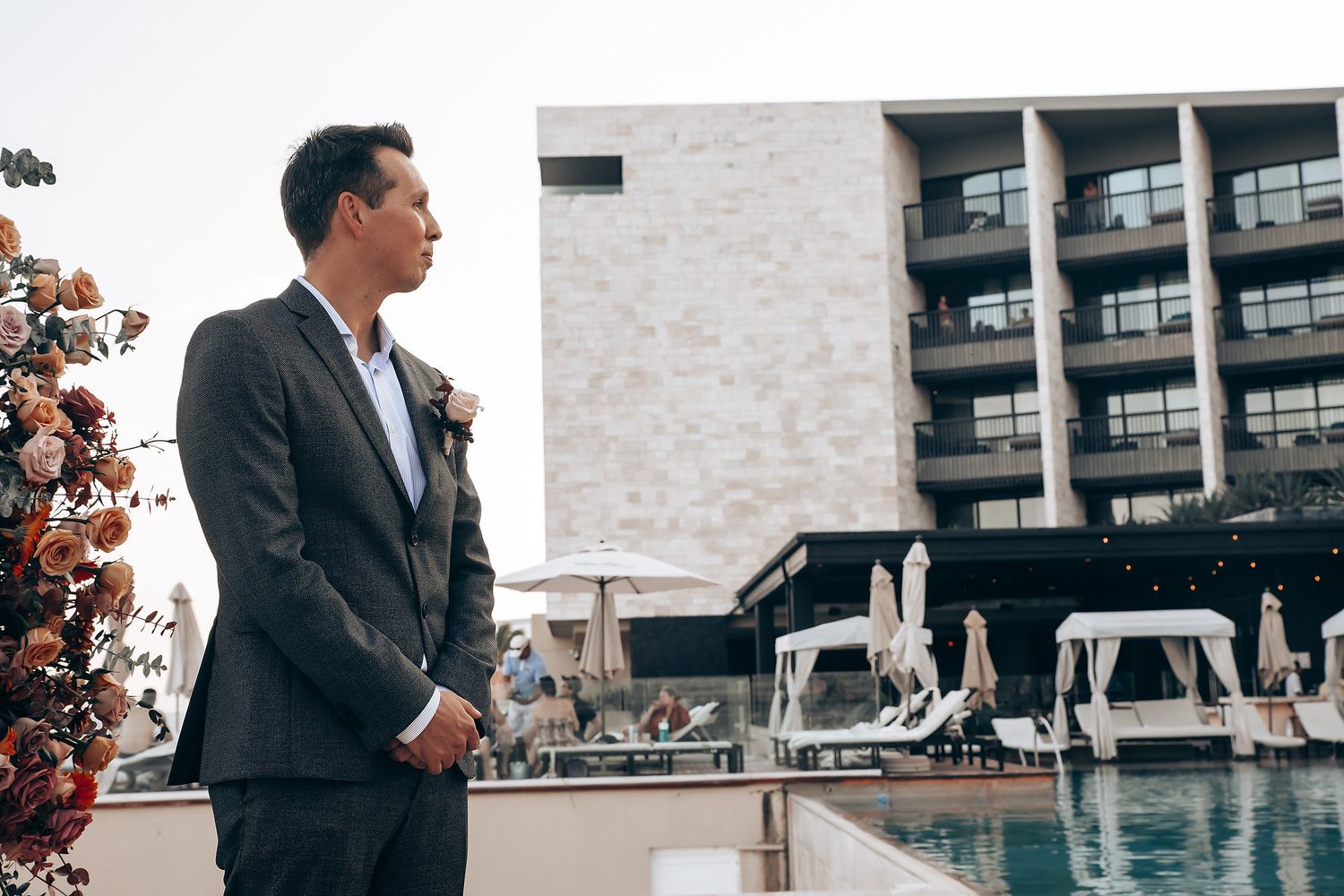 Modern wedding venue exterior with guests gathering near poolside.