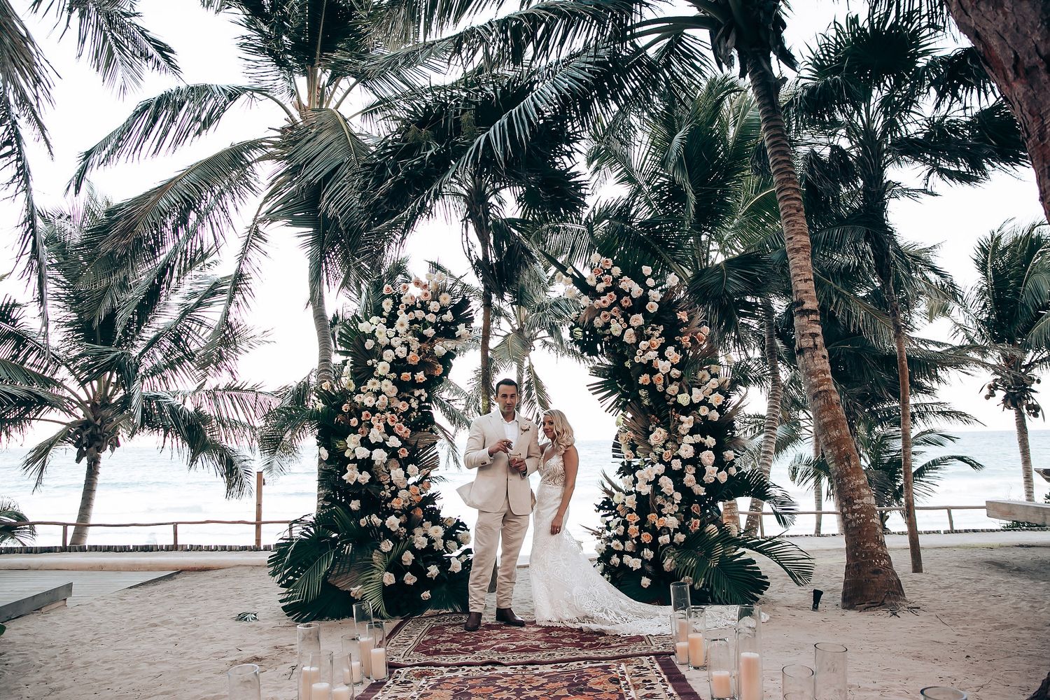 Palm trees and floral arrangements create a tropical wedding ceremony backdrop.