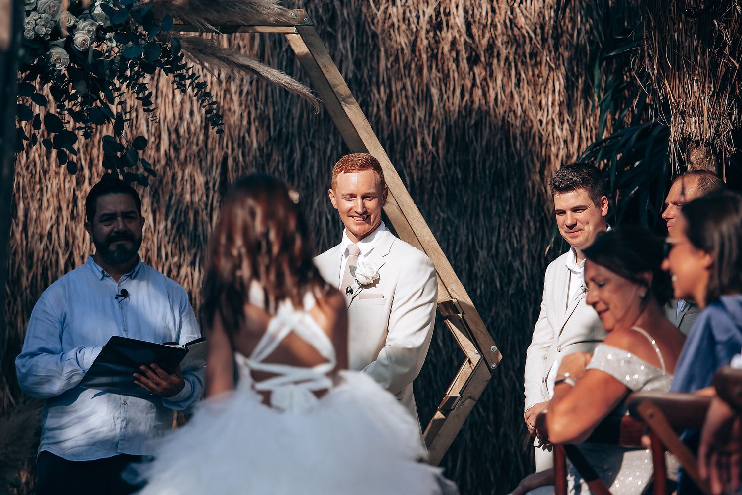Wedding ceremony guests seated outdoors under rustic decor and string lights.