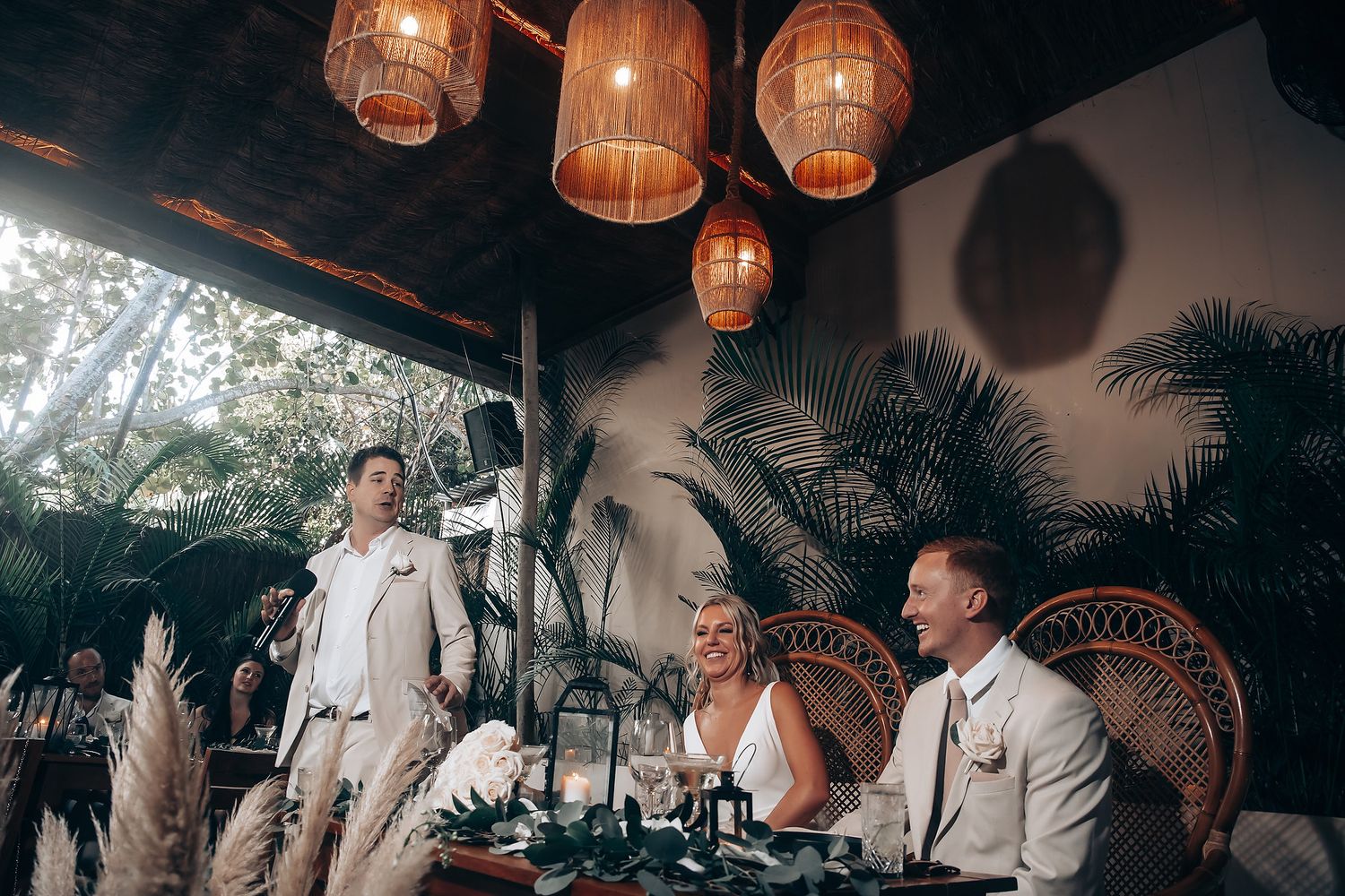 Outdoor wedding venue decorated with warm glowing lanterns and tropical plants creating an intimate atmosphere.