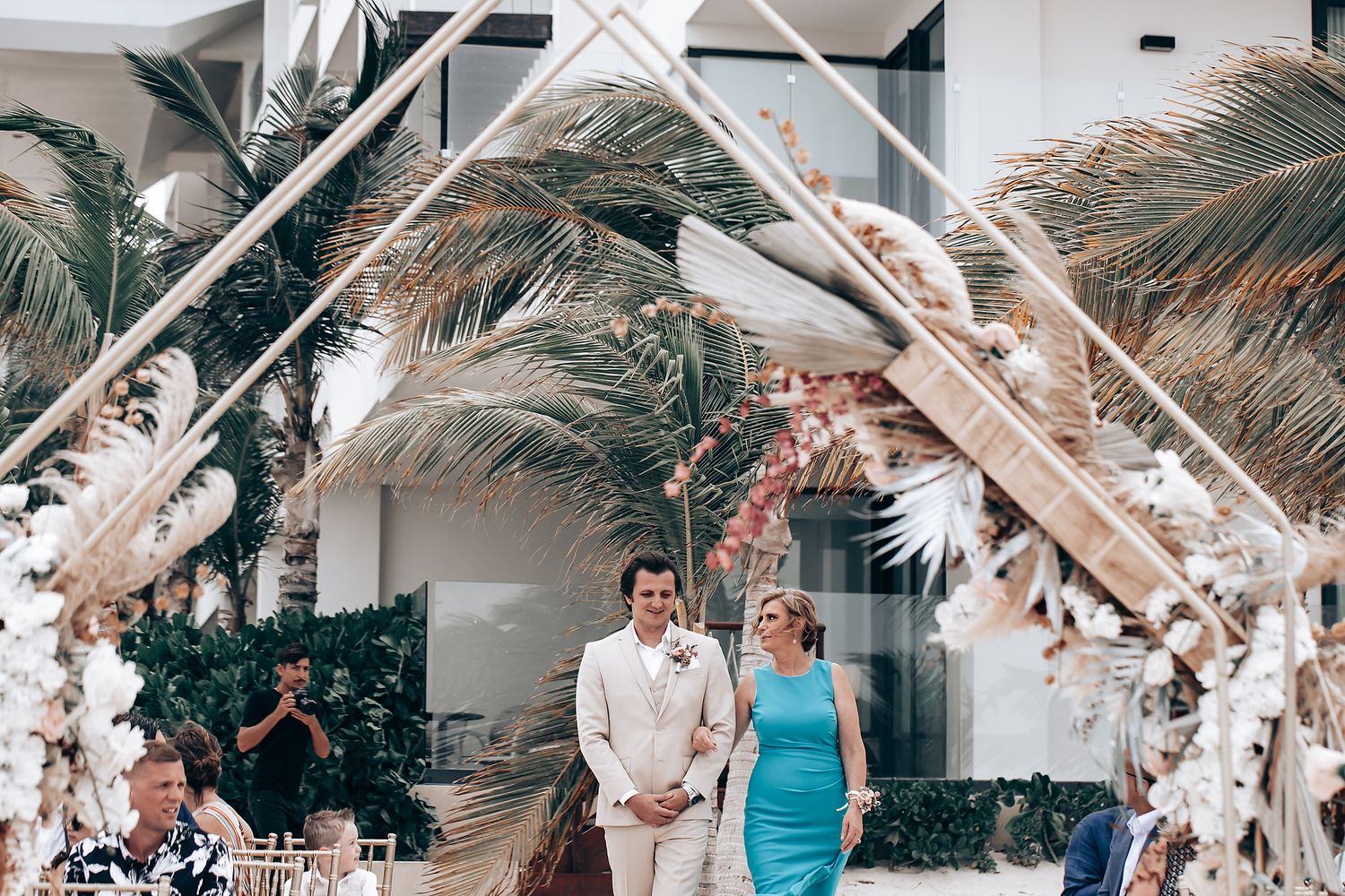White-decorated beach wedding ceremony venue with tropical palm trees and ocean views.