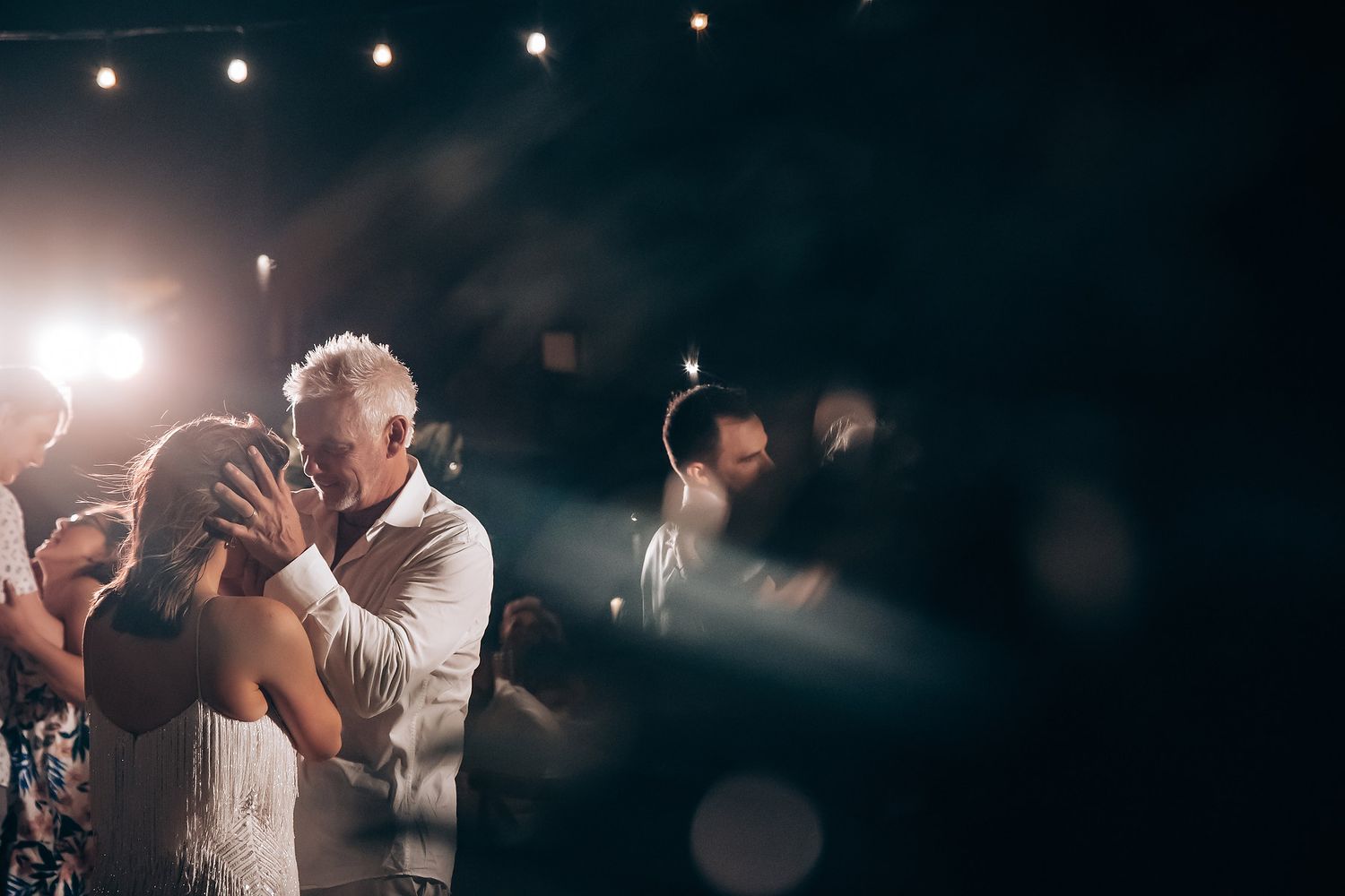 A couple shares a romantic dance under twinkling lights at their evening reception.