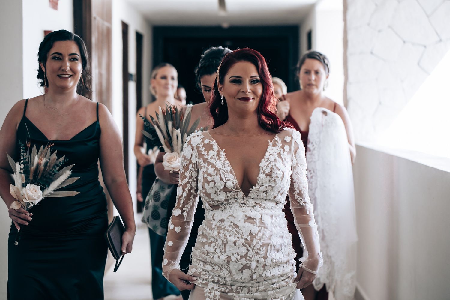 Wedding party walking down a bright hallway in formal attire.