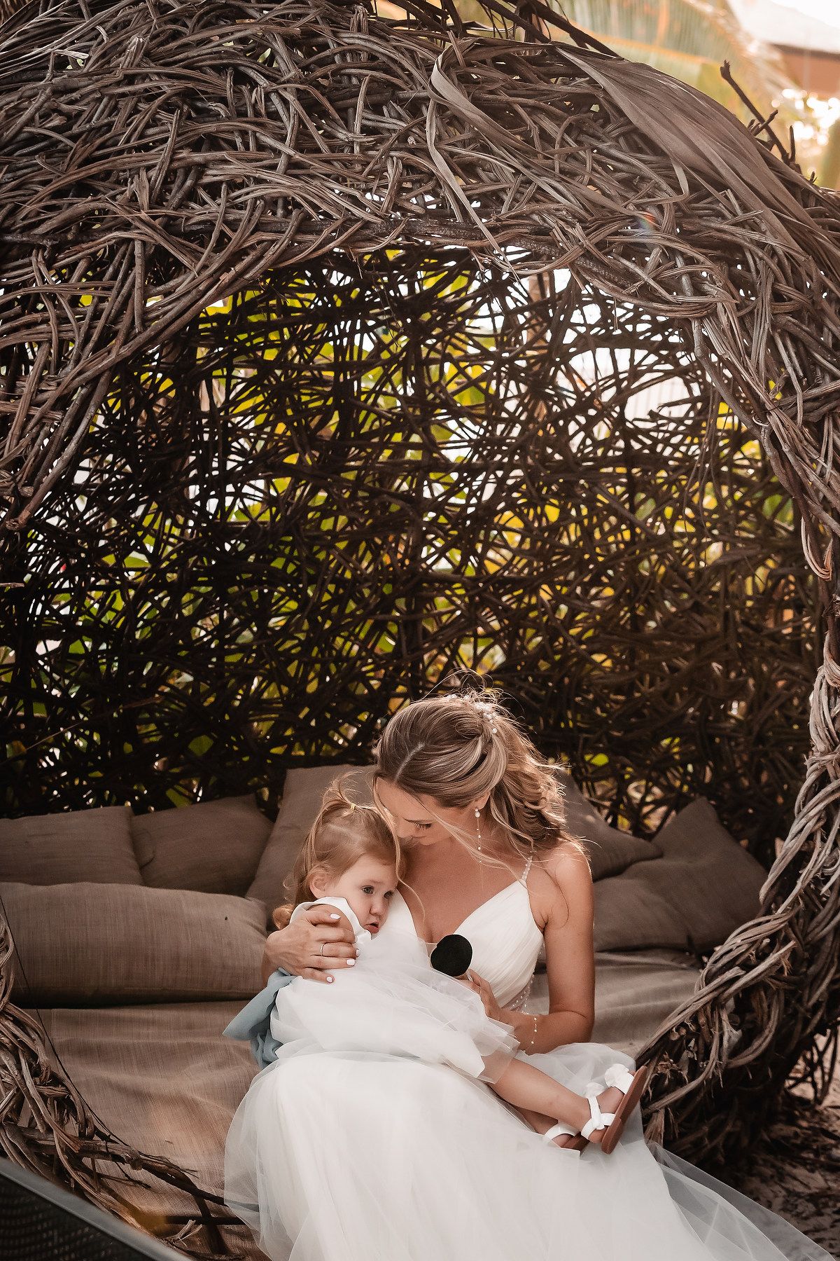 Intimate wedding moment captured under a woven natural arch with soft lighting.