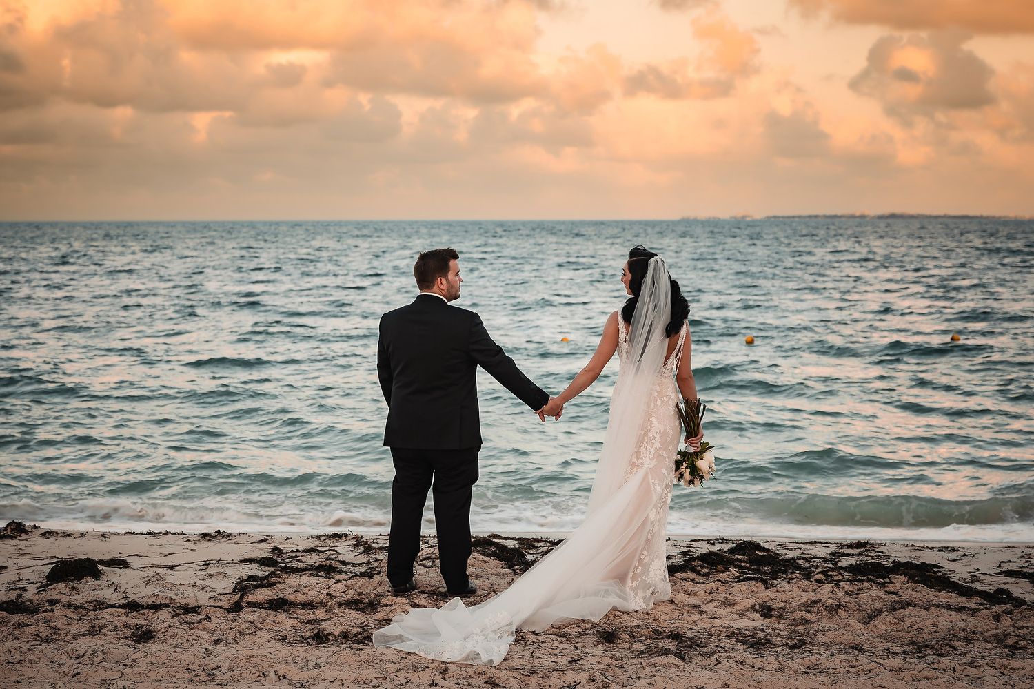 Newlyweds share intimate moments on a beach during a stunning sunset.