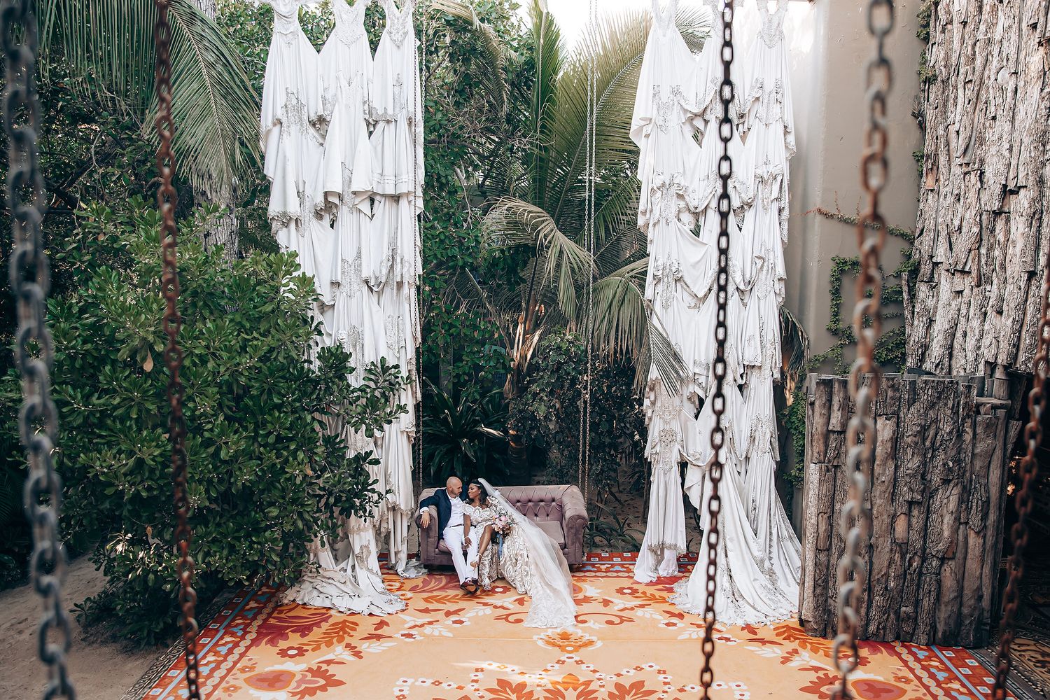 A couple walks through a rustic outdoor wedding venue decorated with hanging lights and autumn leaves.